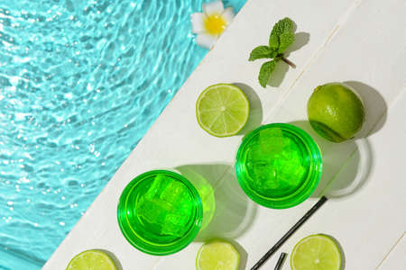 Glasses of fresh lime soda near swimming pool