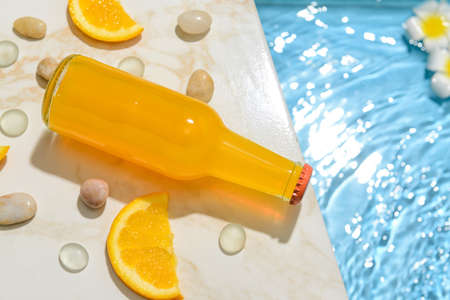 Bottle of fresh orange soda on edge of swimming poolの写真素材