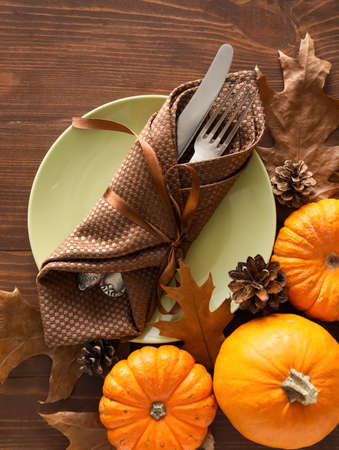 Composition with table setting, pumpkins and autumn leaves on wooden backgroundの写真素材