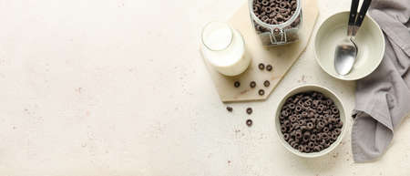 Composition with tasty cereal rings and milk on light background with space for text