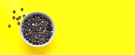 Bowl of tasty cereal rings with milk on yellow background with space for text, top viewの写真素材