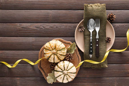 Composition with table setting, pumpkin and autumn leaves on dark wooden backgroundの写真素材