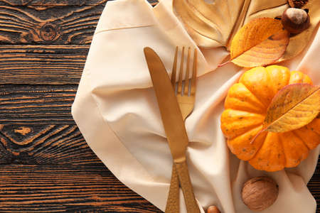 Composition with table setting, pumpkin and autumn leaves on wooden backgroundの写真素材