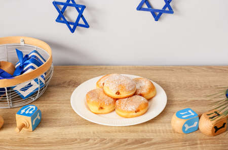 Donuts with dreidels and gifts for Hanukkah celebration on table in roomの写真素材