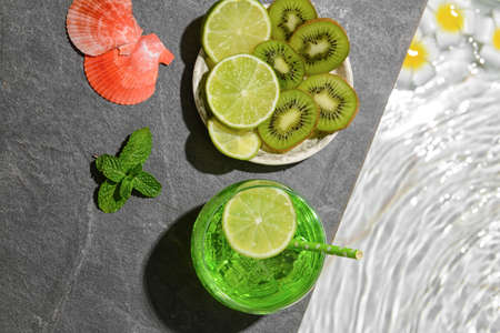 Glass of fresh soda with lime and kiwi near swimming poolの写真素材