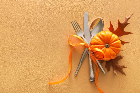 Composition with table setting, pumpkin and autumn leaves on beige backgroundの写真素材