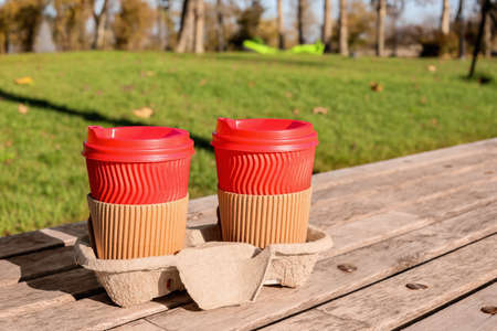 Takeaway cups of tasty latte on bench in parkの写真素材