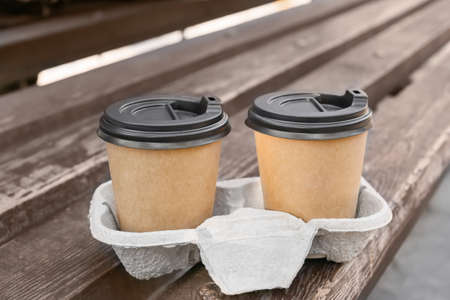 Takeaway cups of tasty latte on bench in park