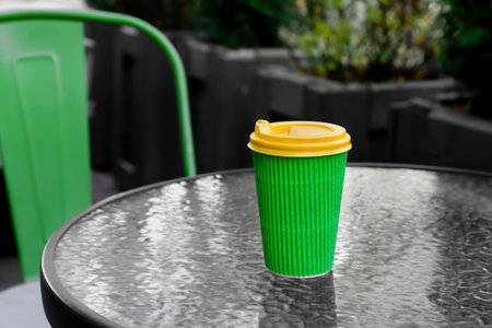 Takeaway cup of tasty latte on table in outdoor cafeの写真素材