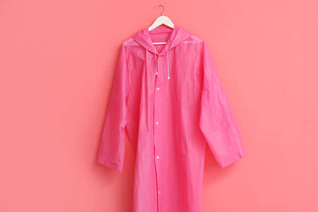 Stylish raincoat hanging on pink wallの写真素材