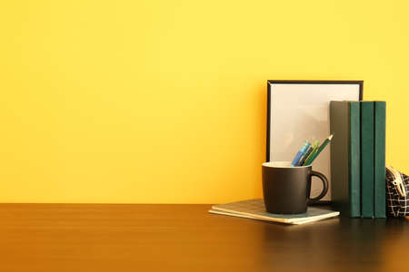 Cup with pencils and books on table near color wallの写真素材