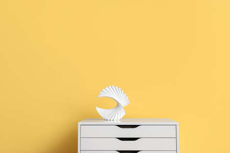 Stylish decor on chest of drawers near yellow wall