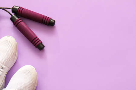 Stylish skipping rope and shoes on purple backgroundの写真素材