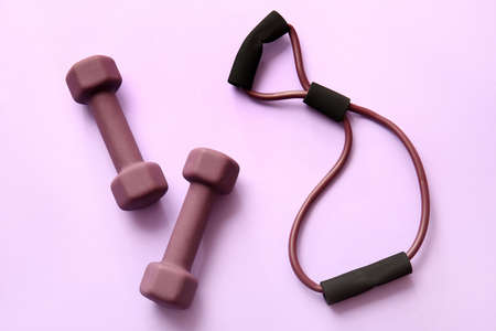 Stylish dumbbells and fitness expander on purple backgroundの写真素材