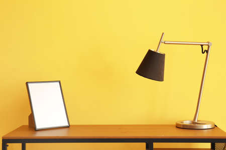 Workplace with modern lamp and blank photo frame near color wallの写真素材