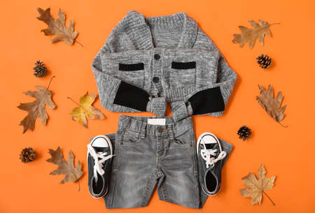 Set of warm kid clothes and autumn decor on color backgroundの写真素材