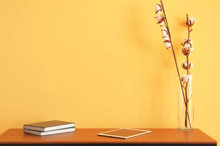 Workplace with tablet computer, books and cotton flowers near color wallの写真素材
