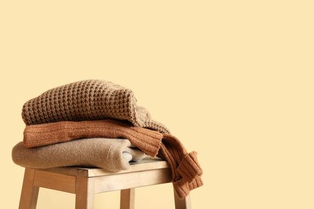 Stylish winter clothes on stool against color backgroundの写真素材