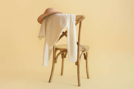 Stylish winter clothes on chair against color backgroundの写真素材