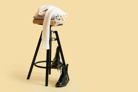 Stylish winter clothes on stool against color backgroundの写真素材
