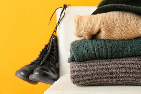 Stylish winter clothes on chair against color background, closeupの写真素材