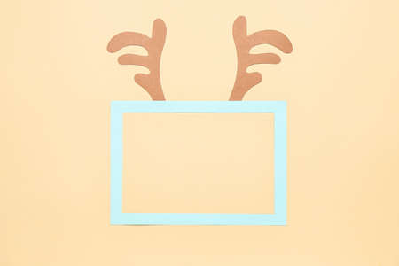 Blank frame and cute reindeer horns on color background