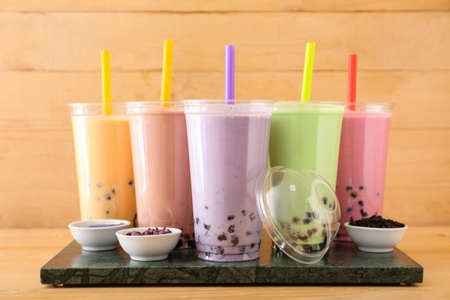 Board with plastic cups of different tasty bubble tea on tableの写真素材