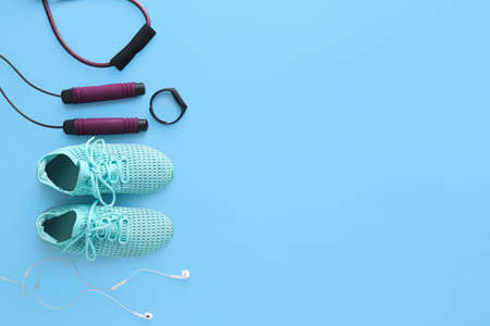 Sports equipment, shoes and earphones on color background