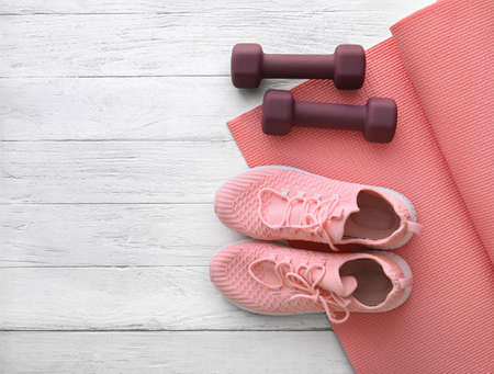 Dumbbells, yoga mat and shoes on light wooden backgroundの写真素材