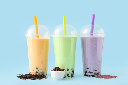 Plastic cups of different tasty bubble tea on blue backgroundの写真素材