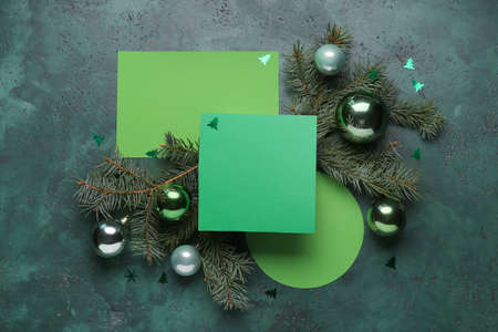 Blank green cards, fir branches and Christmas balls on green background