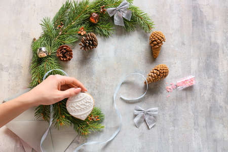 Woman decorating beautiful Christmas wreath made of fir branches on table