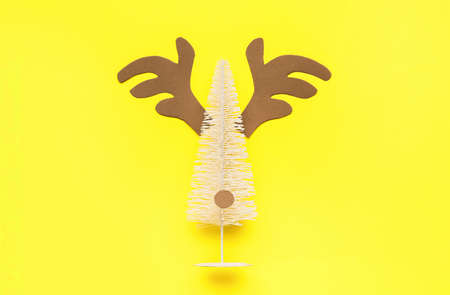 Creative composition with reindeer face made of small Christmas tree and horns on color backgroundの写真素材