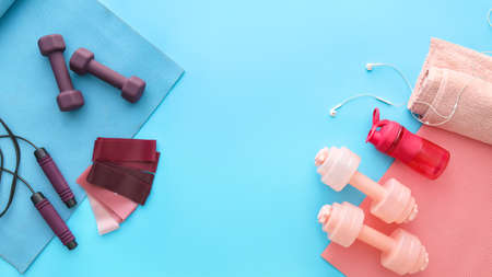 Different sports equipment and earphones on color background