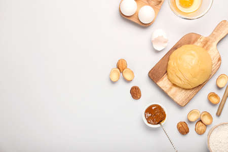 Wooden board of fresh dough for preparing walnut shaped cookies with boiled condensed milk and...
