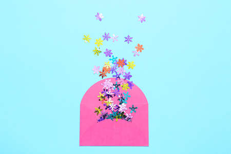 Envelope with confetti in shape of snowflakes on color background