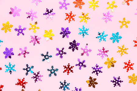 Colorful confetti in shape of snowflakes on pink backgroundの写真素材