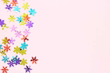 Colorful confetti in shape of snowflakes on pink background