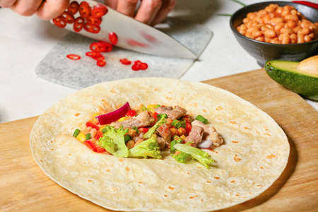 Tortillas with fresh ingredients for preparing tasty burrito on white background