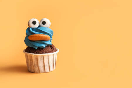 Tasty funny cupcake for Halloween celebration on color background