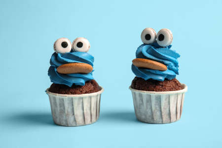 Tasty funny cupcakes for Halloween celebration on blue background