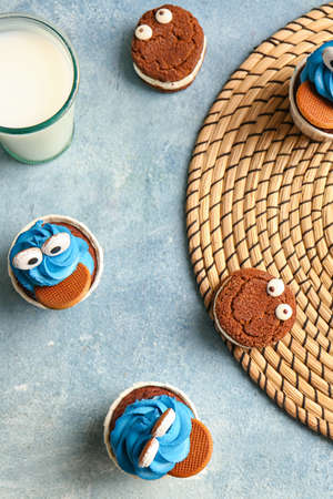 Tasty funny cupcakes and glass of milk for Halloween celebration on color backgroundの写真素材