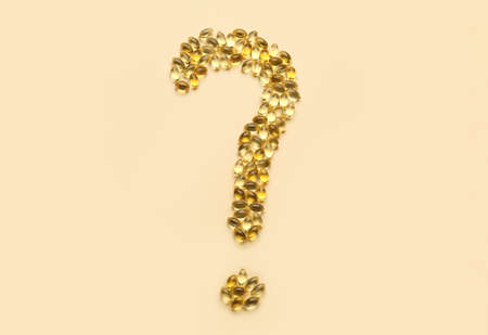Question mark made of fish oil pills on color background
