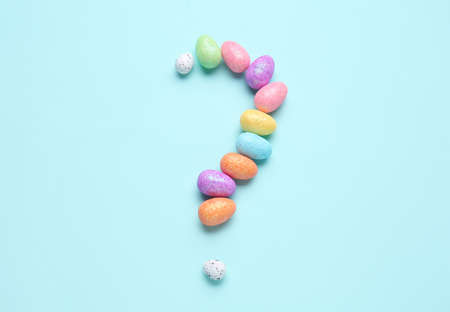 Question mark made of decorative eggs on color background