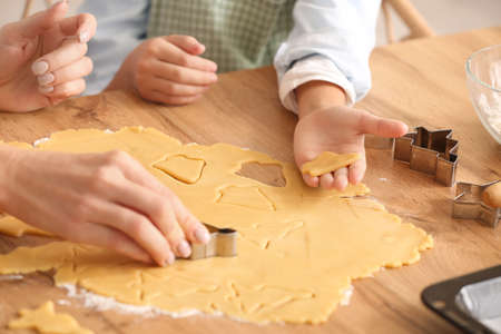 Little girl with her grandmother cutting dough for cookies in kitchen, closeupの写真素材