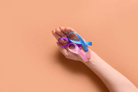 Female hand with different awareness ribbons on beige background. World Cancer Dayの写真素材