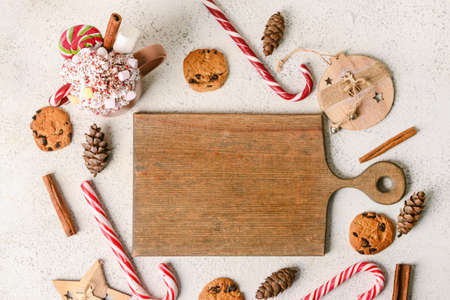 Composition with cup tasty cacao, candy canes, wooden board and cookies on light backgroundの写真素材
