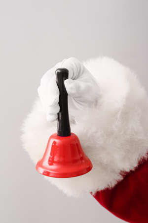 Santa hand with Christmas bell on light backgroundの写真素材