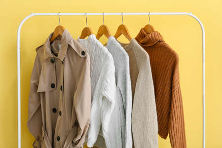 Rack with stylish warm clothes near yellow wallの写真素材