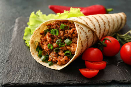Slate plate with tasty burrito on dark background, closeupの写真素材